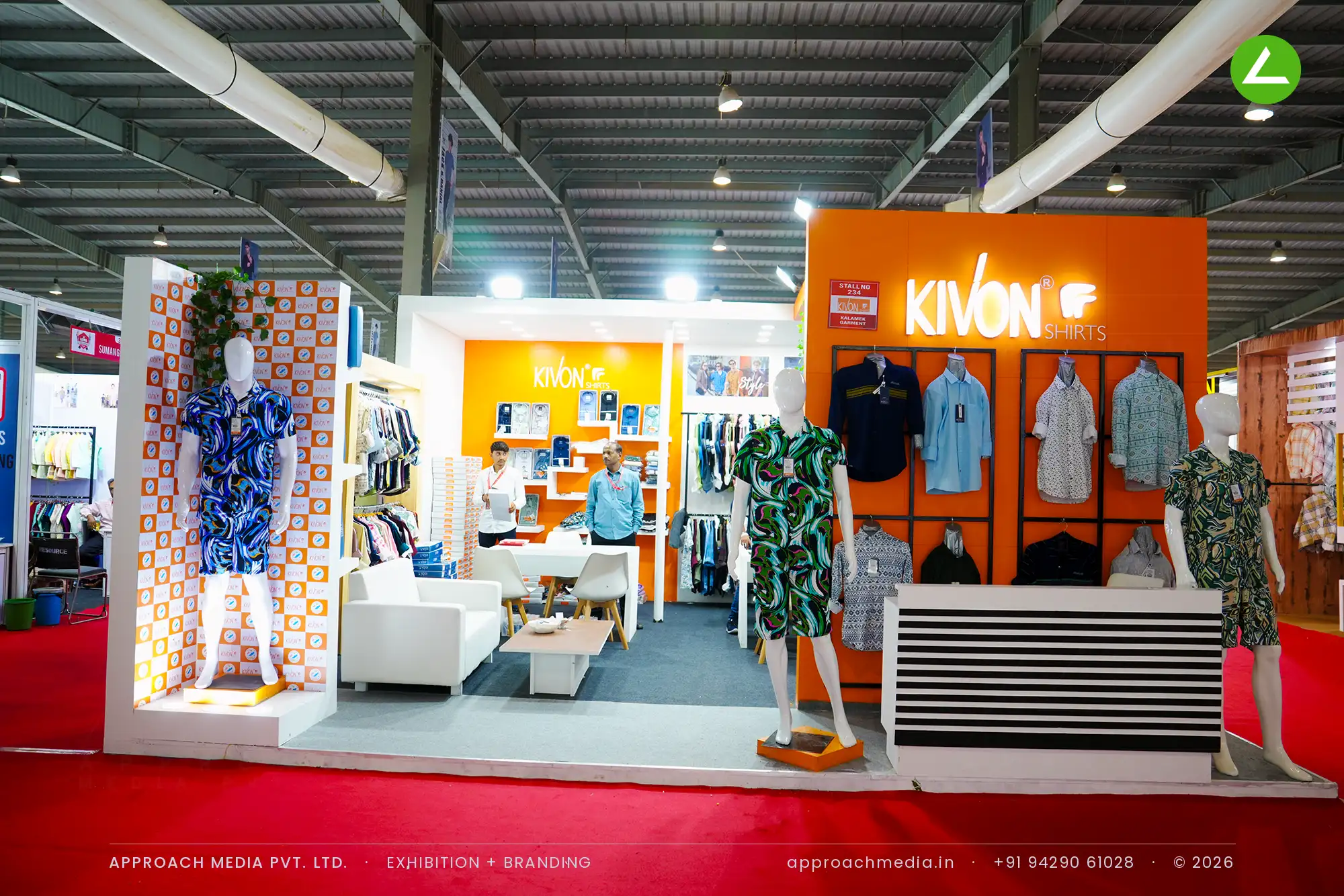 Kivon's orange corner stall with shirts on a black grid wall and mannequins on low plinths, GGMA Garment Fair Gandhinagar