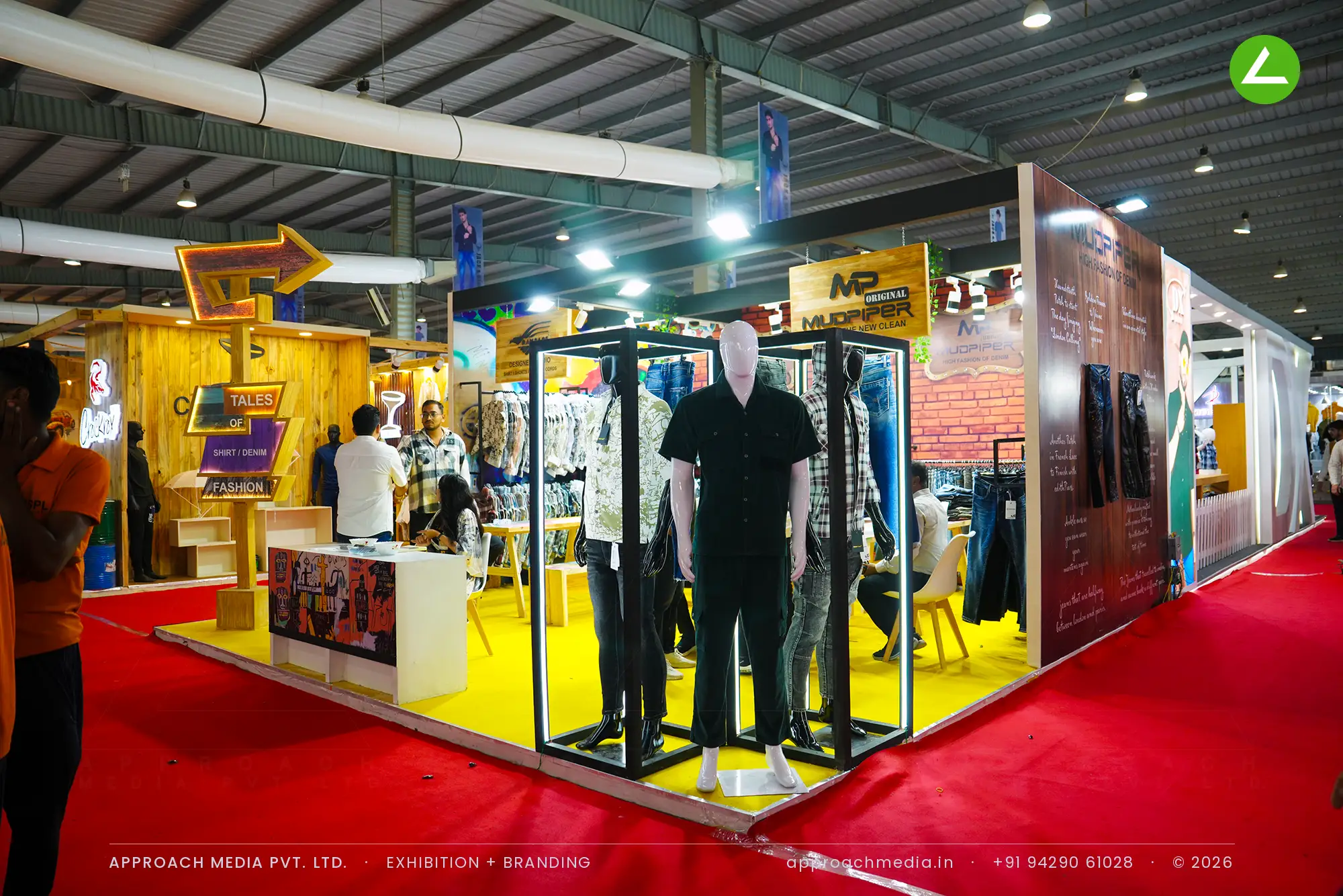 Mudpiper's brick and graffiti stall with caged mannequins below a lit arrow signpost, GGMA Garment Fair Gandhinagar