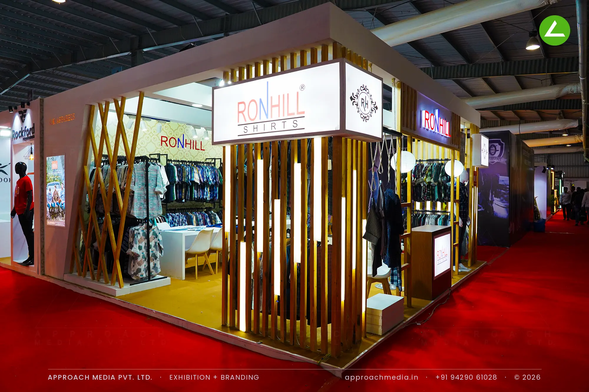 Ronhill's stall at the GGMA Garment Fair, with a lit wooden batten screen and a four-sided logo cube at the corner