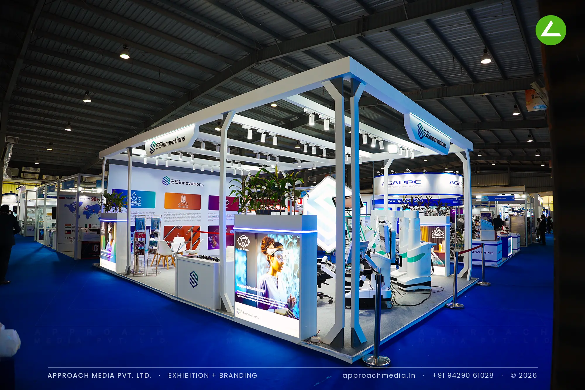 SSInnovations' white pergola stall at MedTech Expo Gandhinagar, with backlit counters ringing a live robotic surgery system