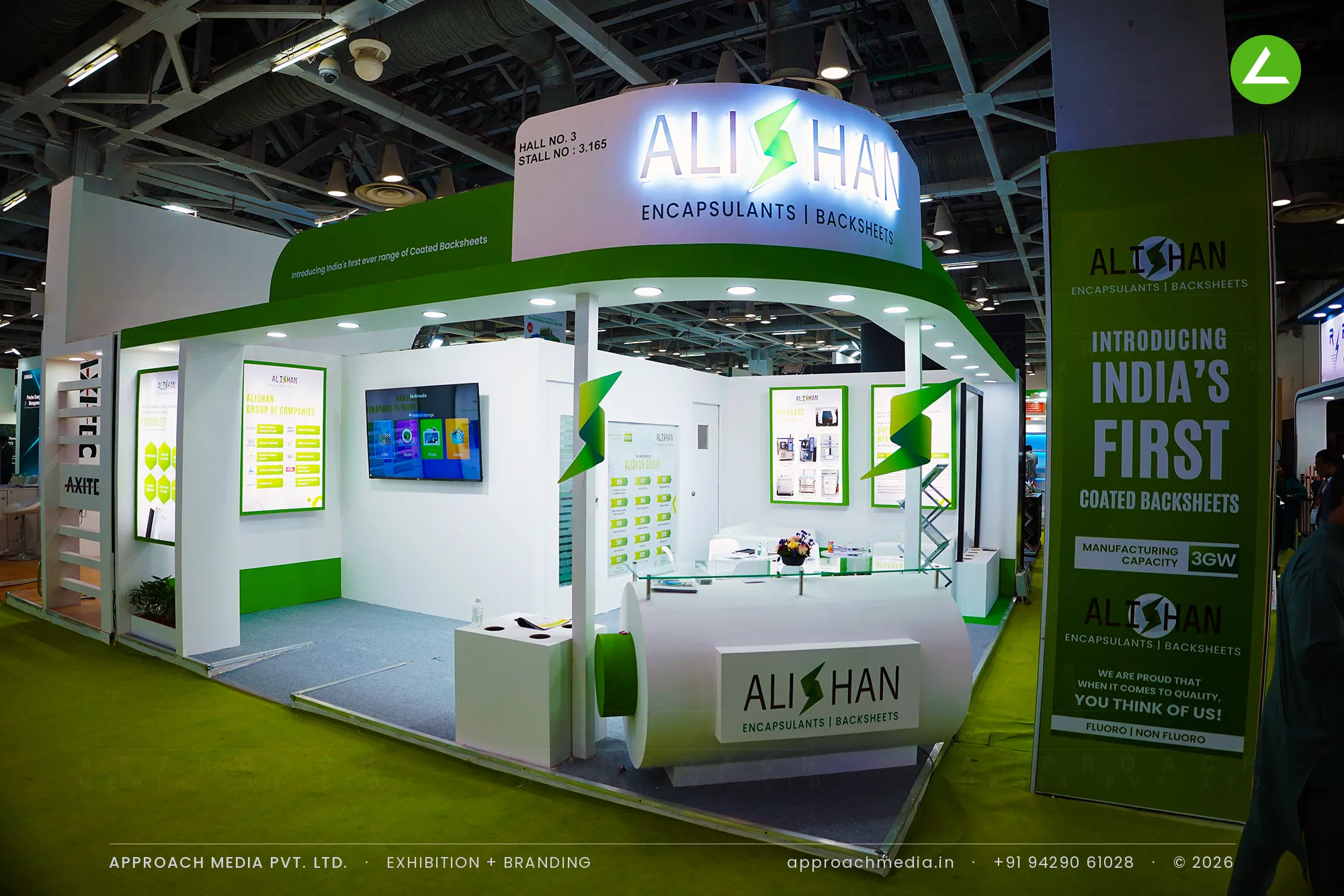 Alishan's green and white stand with oversized branded roll props on the floor under a curved lit fascia disc, Greater Noida