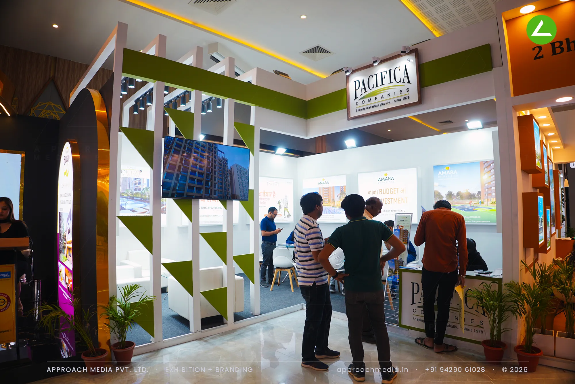 White vertical fins with green infills screen the entrance to Pacifica Companies' stand, a television set into the screen.