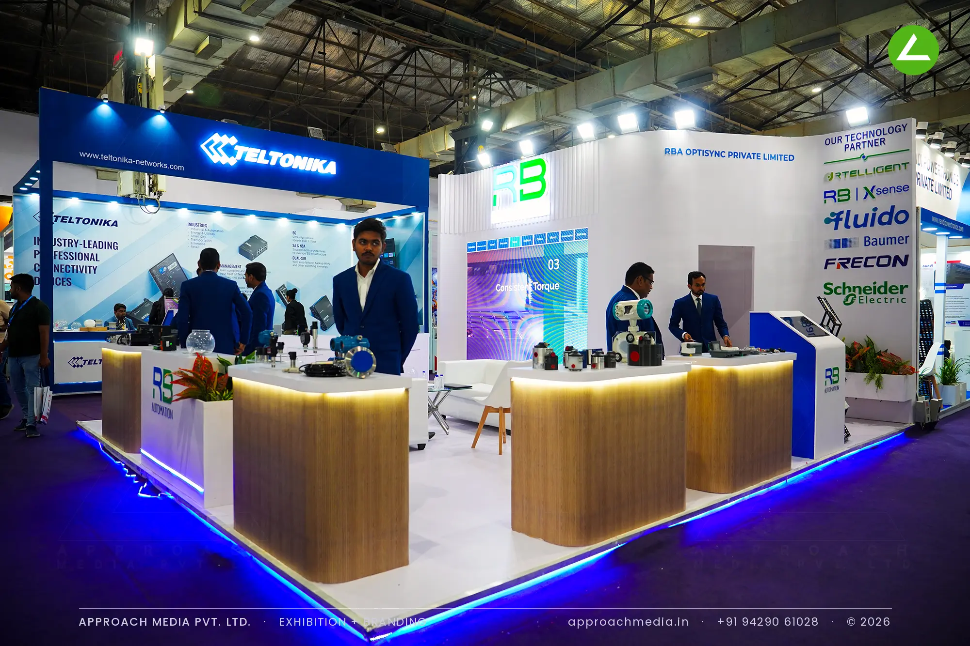 Curved wood counters lit under their tops run through RB Automation's stand, edged by a blue LED strip on a white floor.