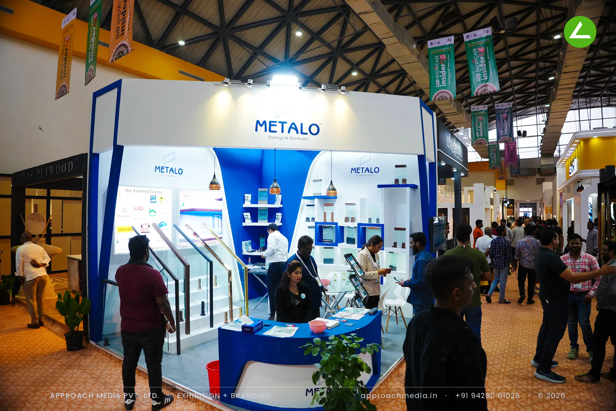 Metalo exhibition stall design at IIID Showcase Hyderabad with a glass-and-brass railing staircase in blue and white