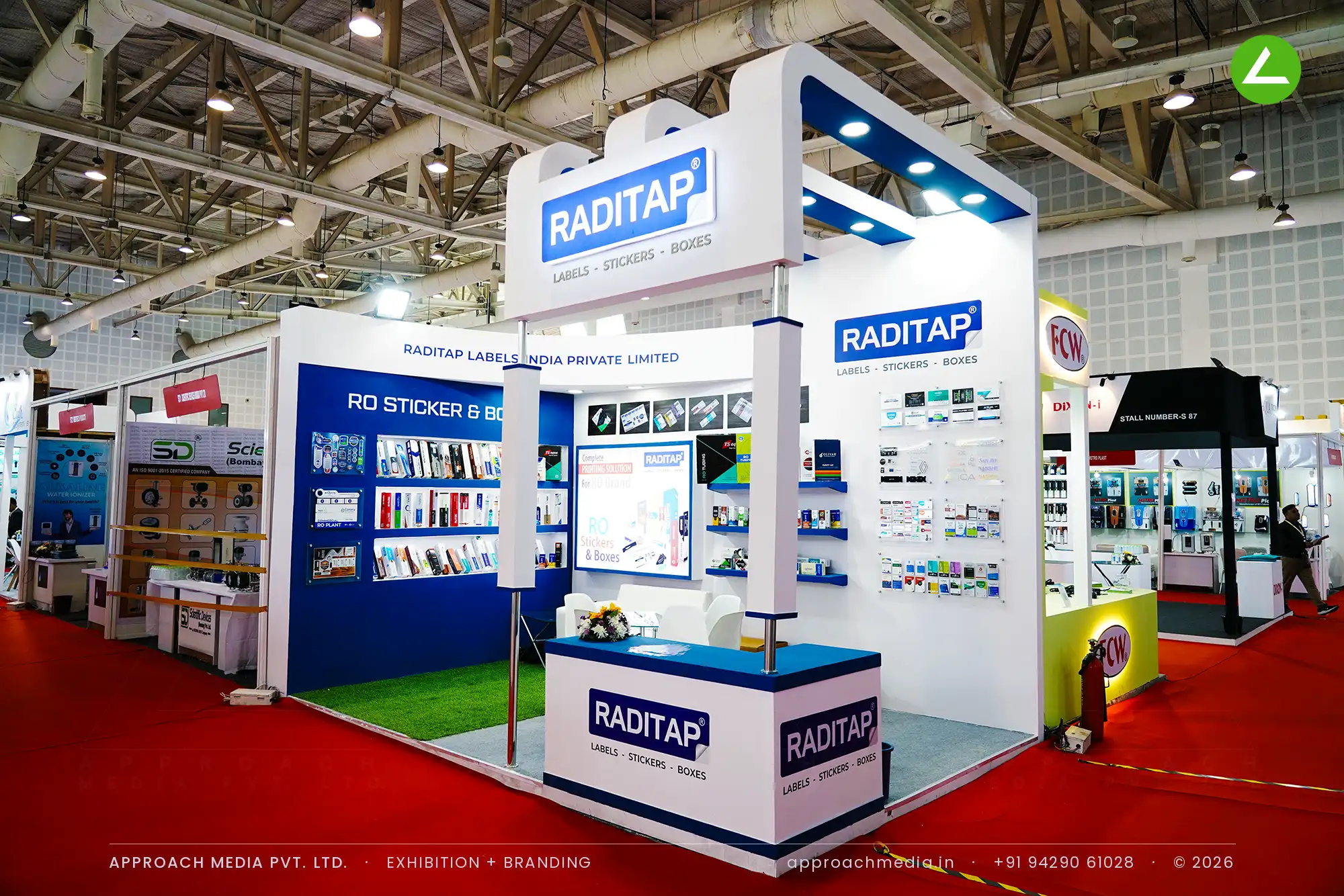 Blue and white Raditap stall at WAPTAG Water Expo, with a curved backlit fascia over walls of fixed label samples