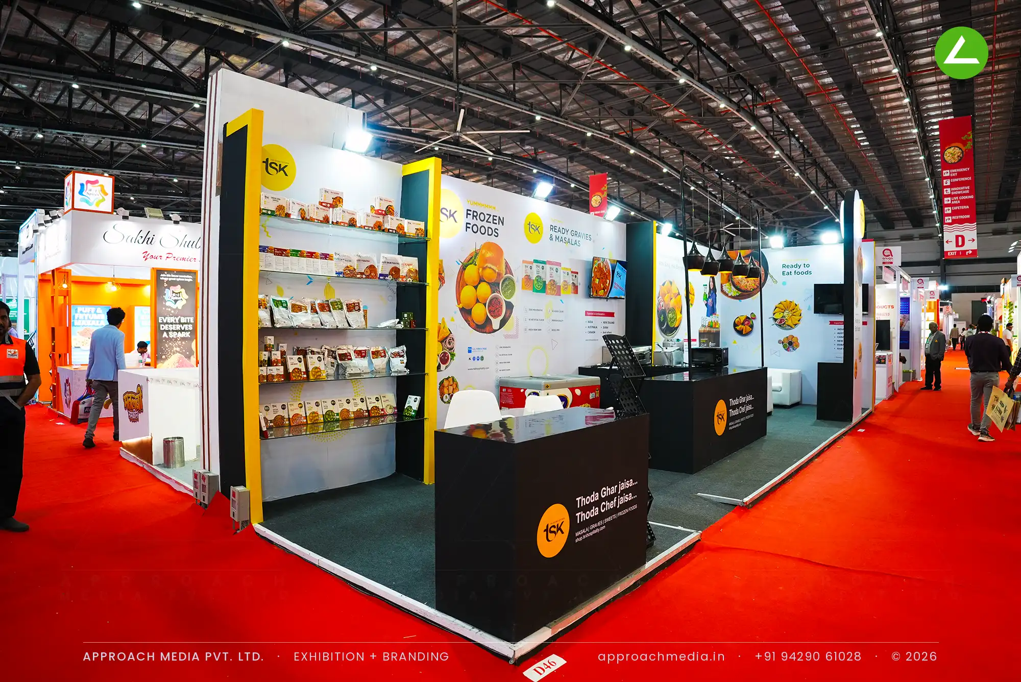 TSK exhibition stall design at AnuFood Mumbai with black counters, retail shelving and lit circular logo discs