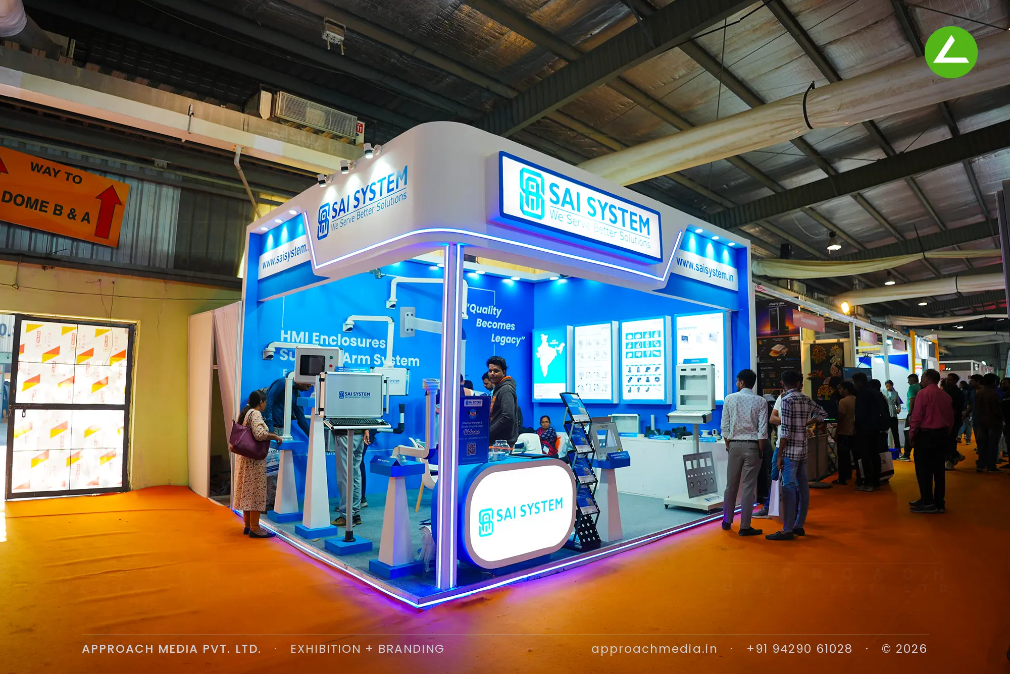 Sai System blue exhibition stall design at EngiMach Gandhinagar with backlit fascia signs and support arm demo pedestals