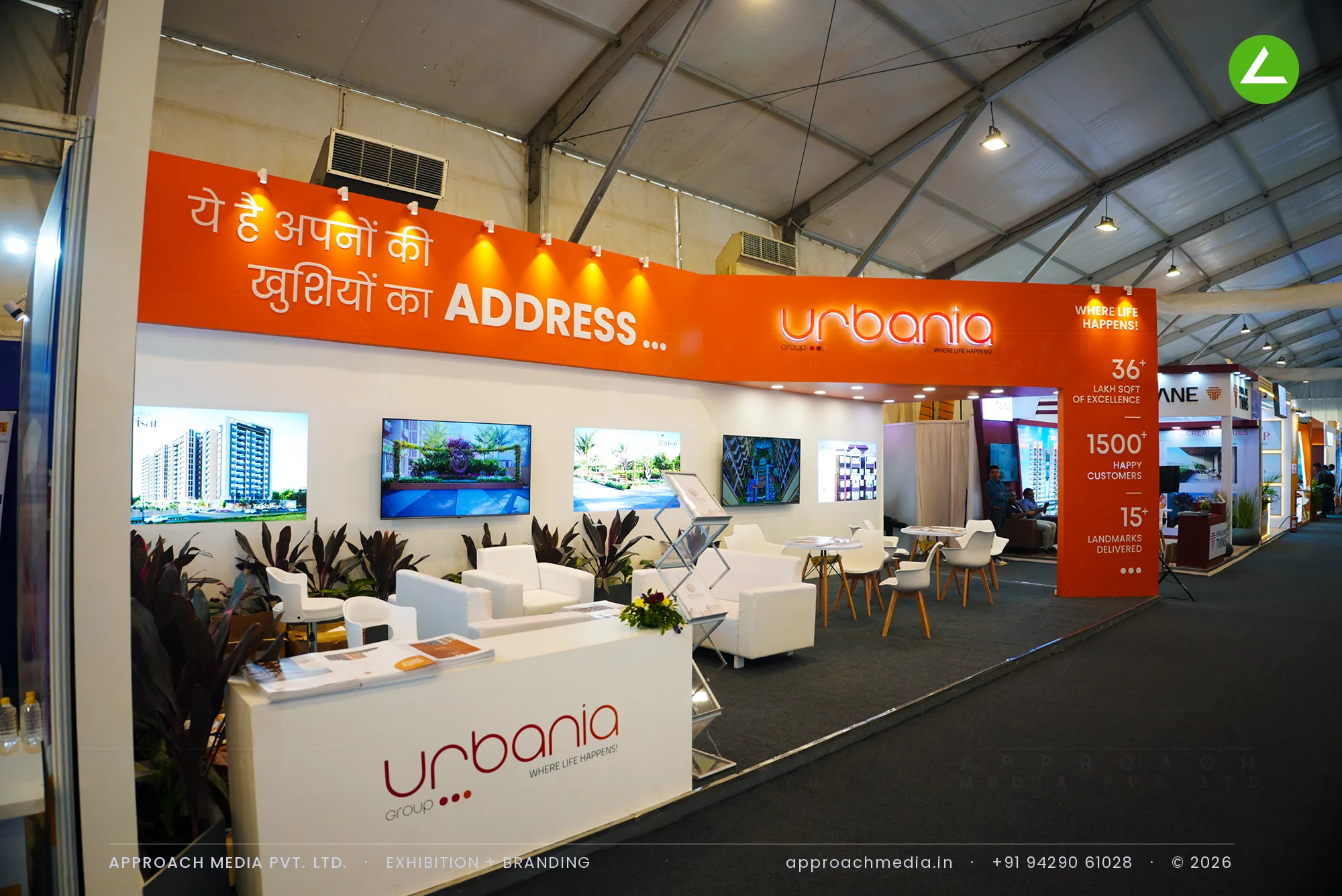 Urbania's stall at the GIHED Tricity Property Expo, an orange headline band running above a white lounge and planters