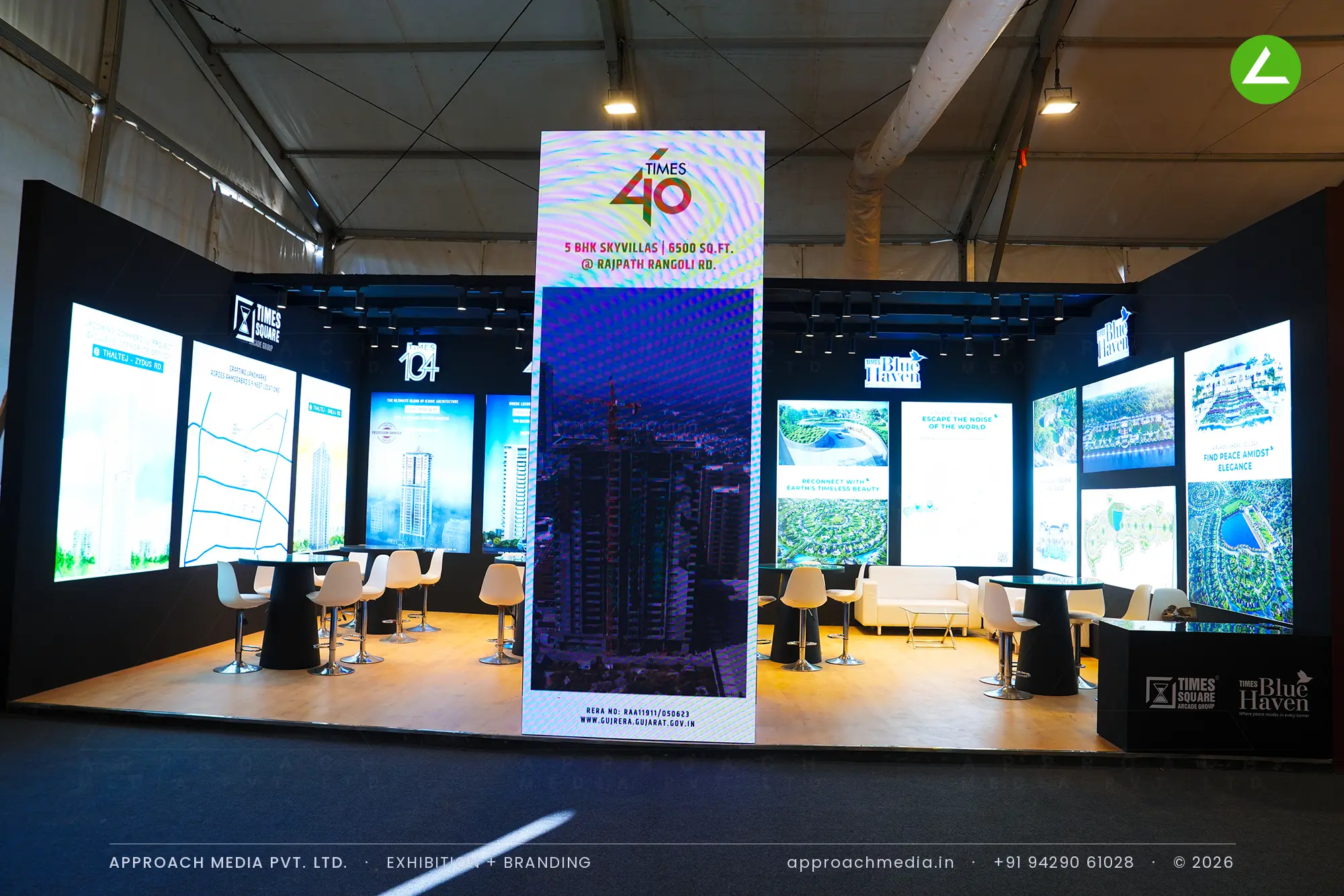 Times Square exhibition stall design at GIHED Property Show Ahmedabad with backlit project panels and central graphic tower