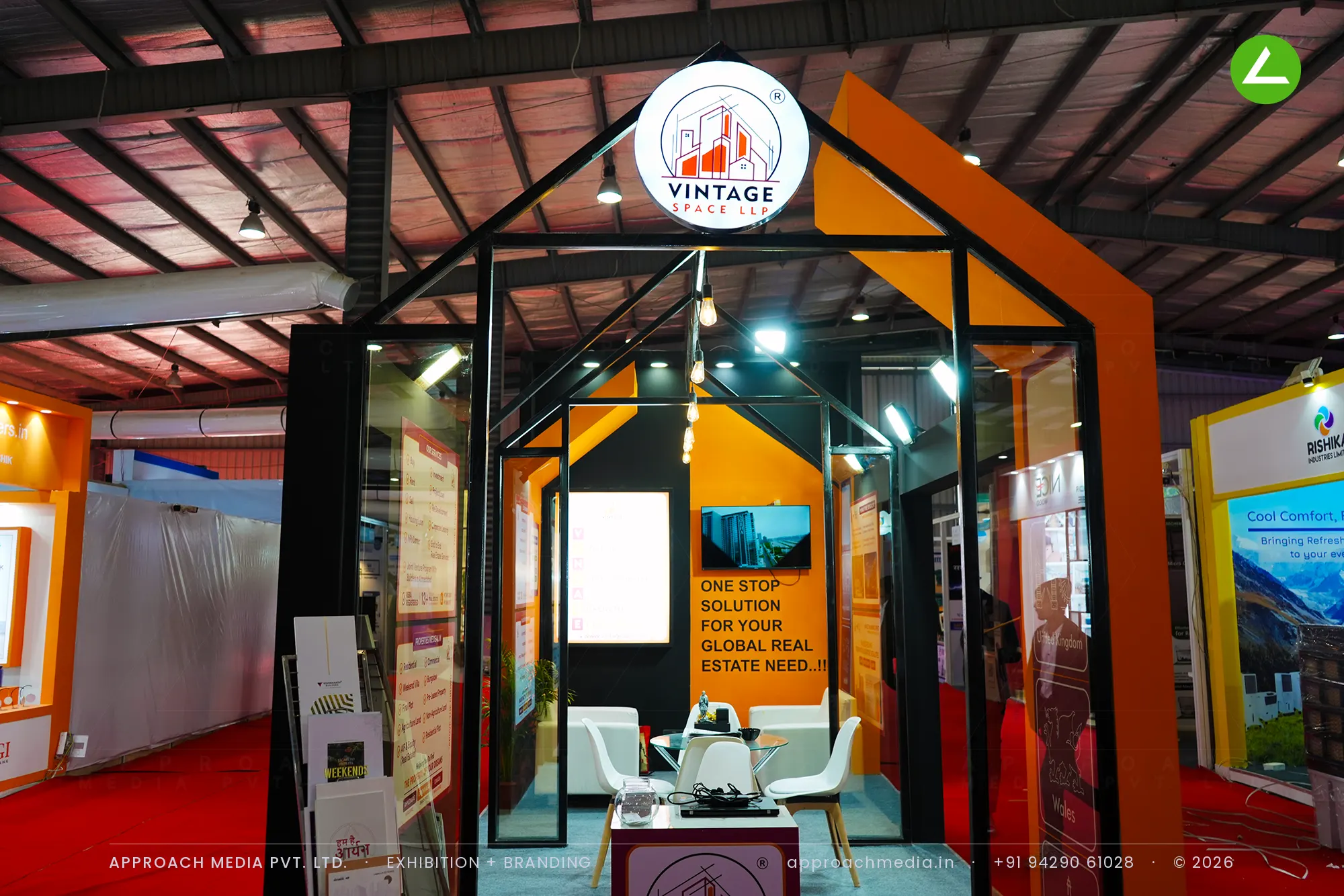 Vintage Space LLP's house-shaped stall at GPBS Gandhinagar, with an orange gable frame and a hanging round logo disc