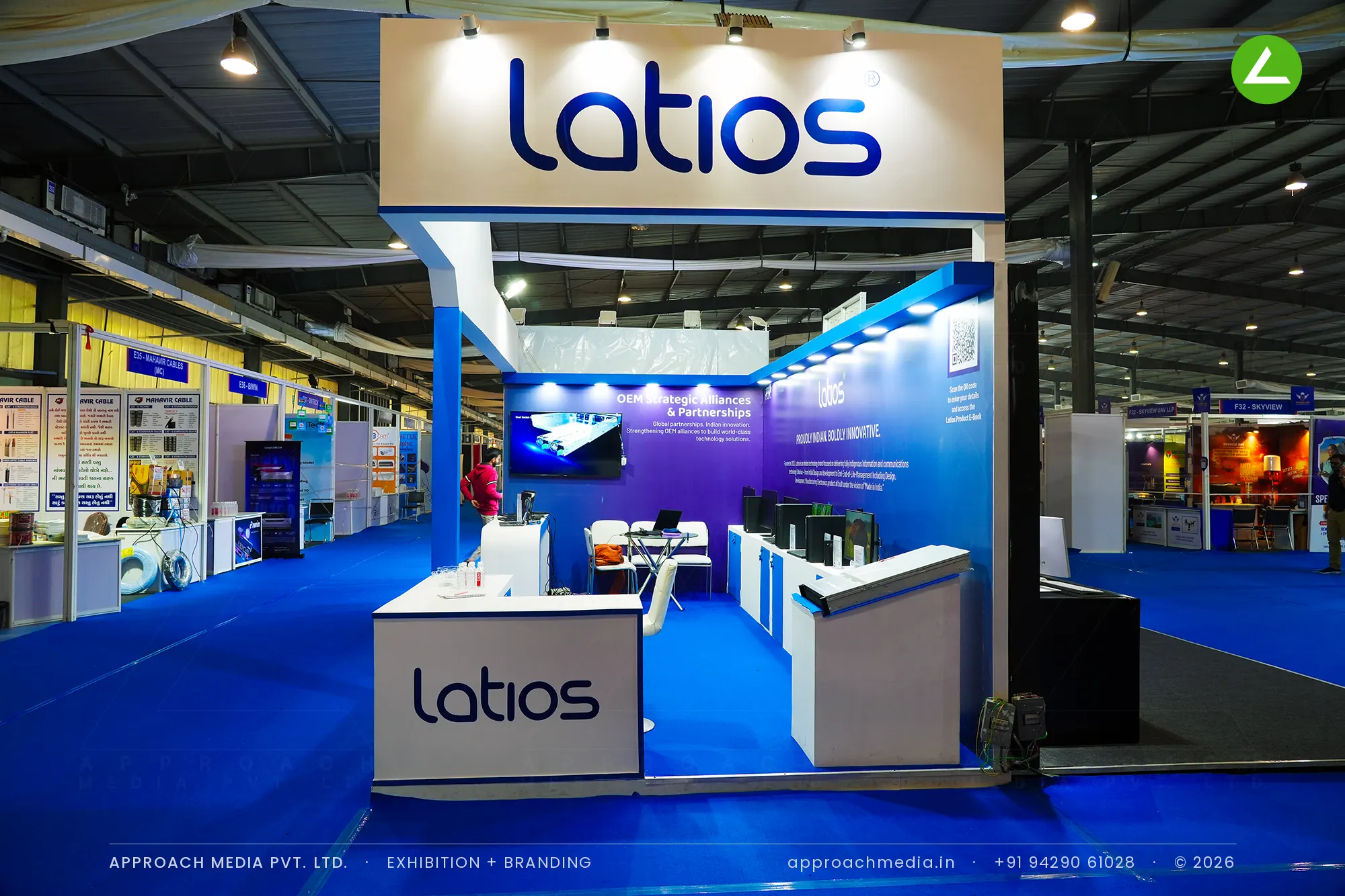 Latios exhibition stall design at FITAG Tech Expo Gandhinagar: raised header over a blue gradient bay — photo 2