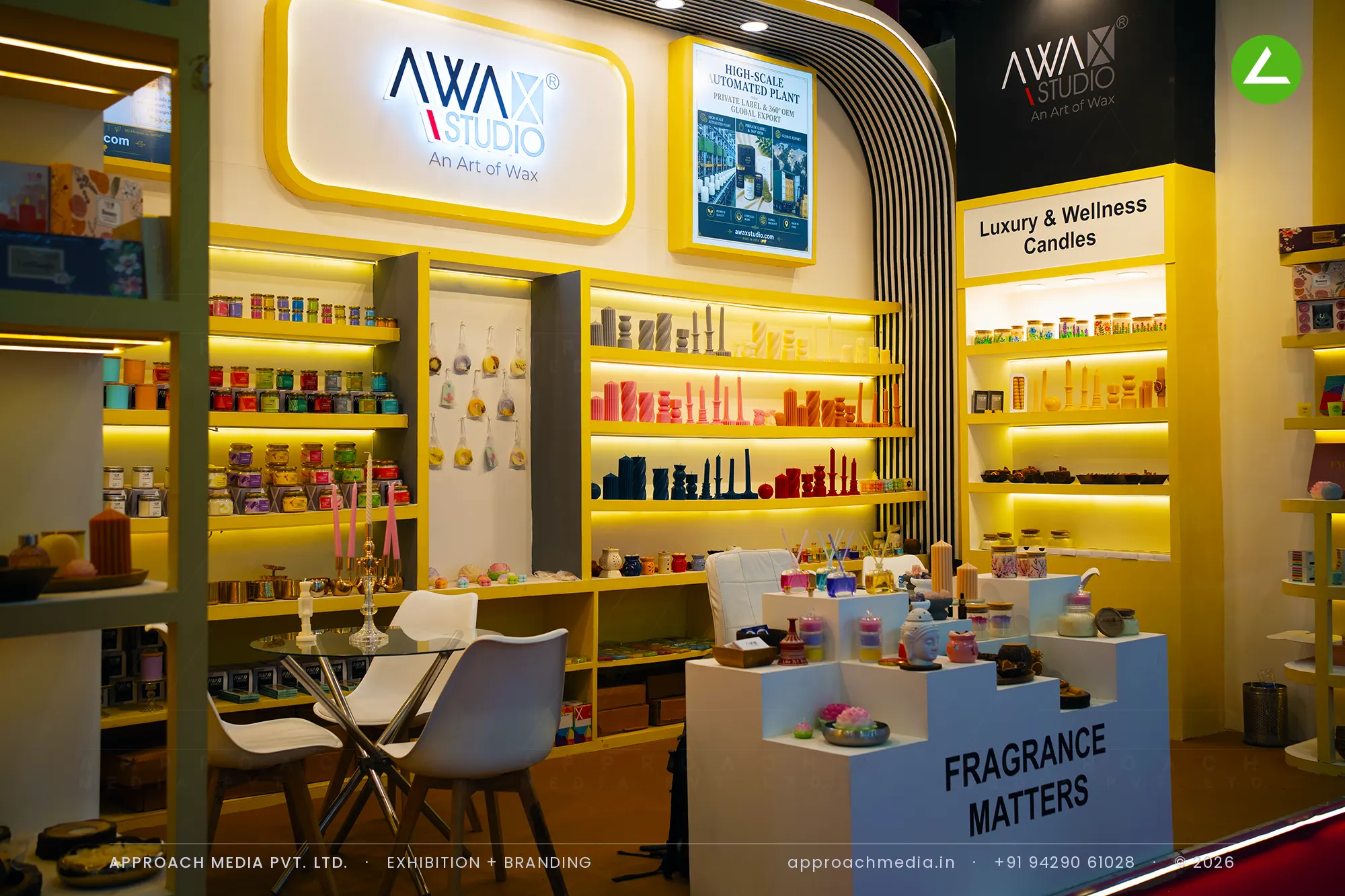 Lit shelf wall of candles behind a tester plinth — exhibition stall design at Gifts World Expo New Delhi for Awax Studio