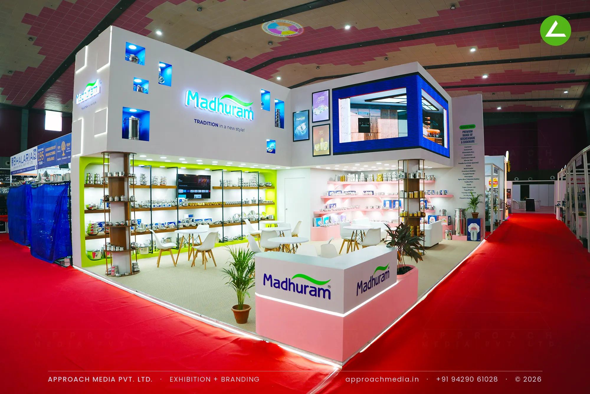 Madhuram's lit fascia over green and pink kitchenware shelving — exhibition stall design at Vibrant India Expo Ahmedabad